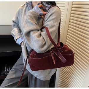 Detail of burgundy matte suede shoulder bag featuring a knotted strap and long leather puller