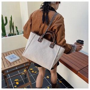 Close-up of cream canvas tote bag with leather trim worn by a model in a cozy setting