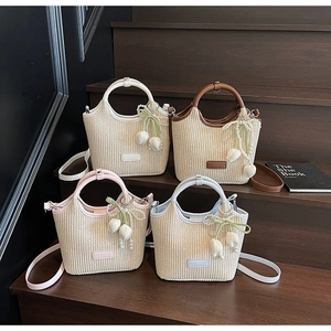Detailansicht bunter Strohtaschen mit Lederbesatz und floralen Perlenanhängern
