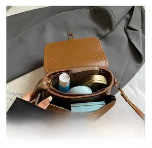 Top-down view of brown retro crossbody bag interior holding phone and cosmetics