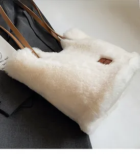 Detail der flauschigen Kunstfellstruktur und braunem Lederriemen der weißen Tasche