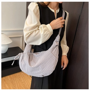 Detail shot of a purple and white striped dumpling cross-body bag with long shoulder strap