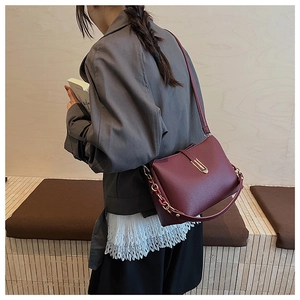 Burgundy litchi grain shoulder bag with gold metal buckle shown on a model