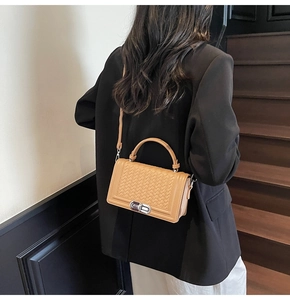 Detail of woven camel leather texture and silver metal twist lock on a shoulder bag