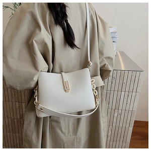 Close-up of white lychee-pattern leather bag with golden metallic clasp and chain strap