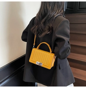 Chic yellow woven shoulder bag shown in an elegant city lifestyle setting on stairs