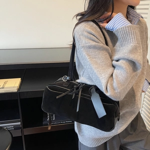 Detail of black matte suede shoulder bag with leather tassels and silver hardware accents