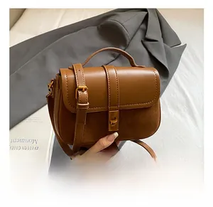 Detail of vintage brown shoulder bag showing golden clasp and textured leather patchwork