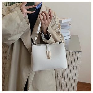 Detail of white litchi pattern leather bag with golden clasp and chain strap