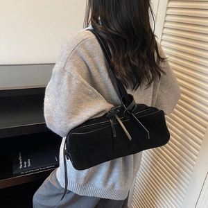 Close-up of black matte shoulder bag with knot detail worn by a model in a minimalist setting