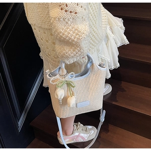 Detail der geflochtenen Eimertasche mit Perlenriemen und Tulpenanhängern auf Holzstufen