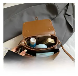 Detailed interior of minimalist brown crossbody bag showing dual compartments for phone and lipstick
