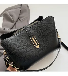 Close-up of black litchi leather bag with gold U-shaped buckle and chain strap detail