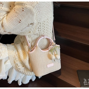 Detail der Mini-Strohkübeltasche mit rosa Ledergriff und süßem Kirsch-Perlenanhänger
