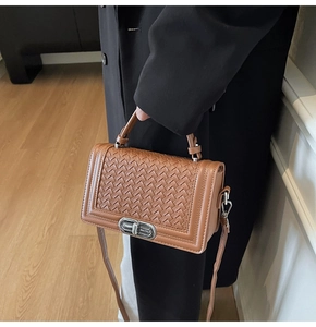 Detailed view of brown woven texture handbag with silver metal twist lock and stitching