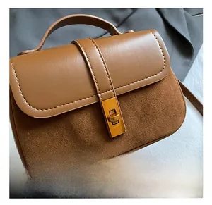 Close-up of retro brown shoulder bag with textured suede panels and golden twist lock