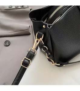 Detail of black lychee leather bag with gold hardware and stylish chain strap