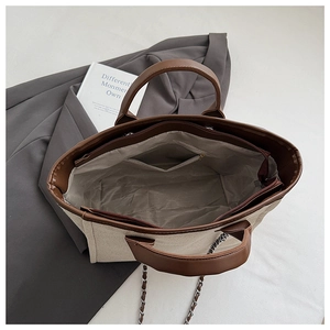 Interior detail of a canvas tote bag with leather trim and a zippered inner pocket