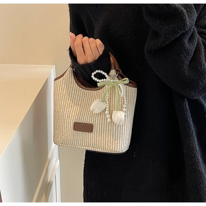 Detail der creme-gewebten Beuteltasche mit Lederbesatz und Tulpen-Perlen-Taschenanhänger