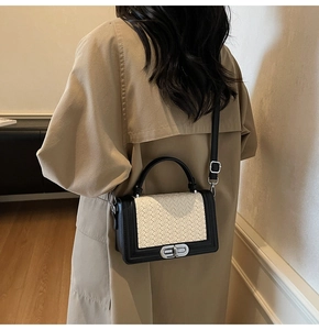 Detail of crossbody bag with black and white woven texture and silver metal clasp
