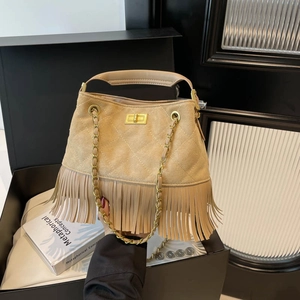 Beige suede tassel handbag with quilted stitching and gold chain strap in a studio shot