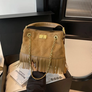 Brown matte suede shoulder bag with long fringe, gold lock, and chain strap in luxury setting