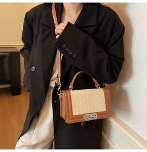 Detail of brown leather and beige woven crossbody bag worn with a dark blazer