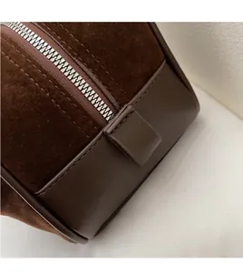 Detail of silver metal zipper and neat stitching on dark brown suede shoulder bag