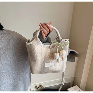 Detail einer handgewebten Beuteltasche mit Blumen-Perlenanhänger und Lederbesatz
