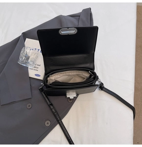 Detailed view of the black flap shoulder bag interior with multi-layer compartments