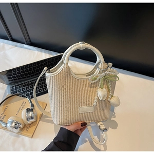 Detail der beigen geflochtenen Eimertasche mit Perlen-Tulpen-Anhänger und Ledergriffen