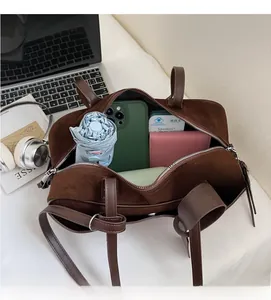 Detail of spacious dark brown suede bowling bag interior holding umbrella and phone