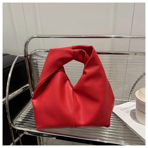 Detailed close-up of a red knotted handle dumpling bag on a metallic shelf display