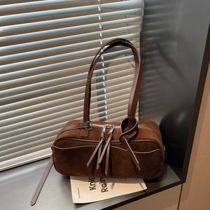 Close-up of deep brown frosted suede shoulder bag featuring long tassel zipper details