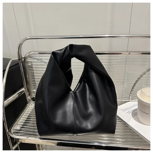 Detailed view of black matte PU leather texture with knot design handle on cloud handbag