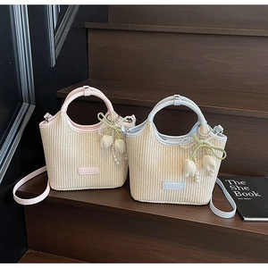 Detail der gewebten Strohhandtasche mit Tulpenanhänger, Perlenkette und Leder-Etikett