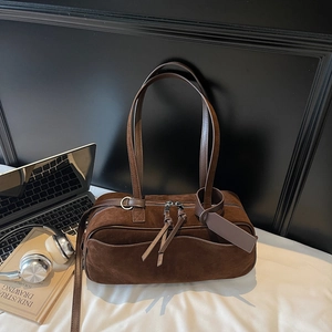Macro shot of dark brown suede-textured bowling bag with silver hardware and smooth straps