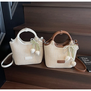 Detail von gewebten Strohhandtaschen mit Lederbesatz und dekorativen Perlenanhängern
