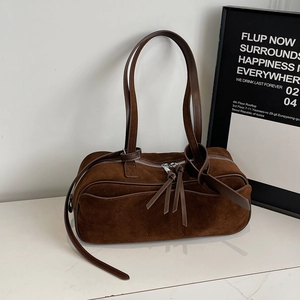 Detail of dark brown suede shoulder bag with silver double zippers and leather tassels