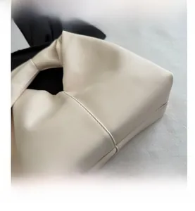Close-up of creamy white ruched dumpling bag showing leather texture and stitching detail