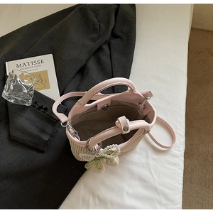 Draufsicht auf eine gewebte Strohhandtasche mit rosa Lederbesatz und Perlen-Kirsch-Anhänger