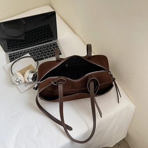 Spacious interior of dark brown suede handbag showing inner zipper pocket and black lining