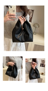 Detail of minimalist black cloud bag featuring a unique knotted handle and pleated PU leather
