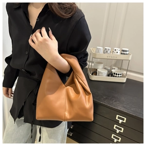 Detail of caramel brown ruched leather handbag with a minimalist pleated cloud design