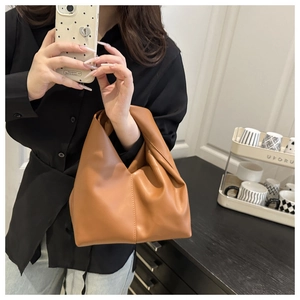 Mirror selfie showing the caramel brown soft leather pleated dumpling bag with single handle