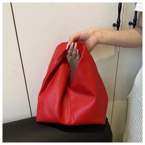 Close-up of a red pleated cloud bag with elegant leather knot detail on the handle