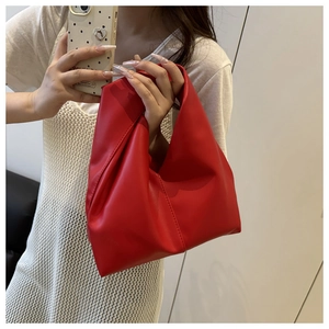 Detail view of red cloud dumpling bag featuring unique knotted handle and soft leather texture