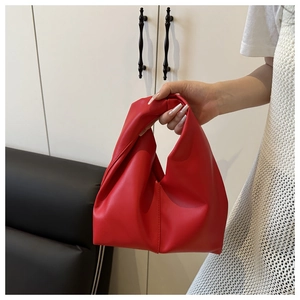 Close-up of bright red pleated dumpling bag with single handle in soft vegan leather