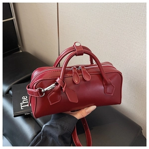 Detail view of burgundy matte leather bag showing top handles and metal zipper closures