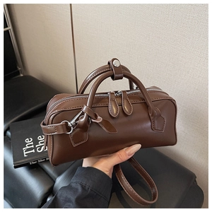 Close-up of a brown leather Boston handbag with silver zippers and durable top handles